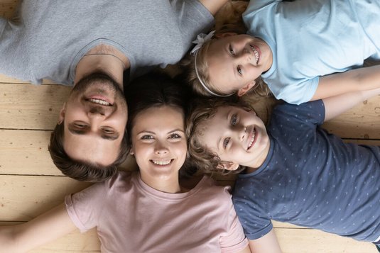 Familie liegt Kopf-an-Kopf auf Boden