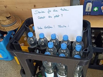 Kasten mit Wasserflaschen und einem Zettel für Handwerker