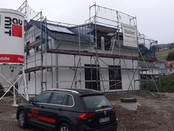 Haus mit Baugerüst neben Silo