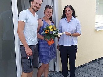 Drei Menschen bei einer Hausübergabe