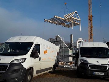 Kran hebt Dach auf Haus