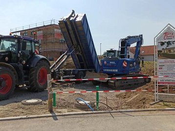 Traktor und Bagger auf Baugrundstück