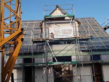 Kran an Haus mit Baugerüst