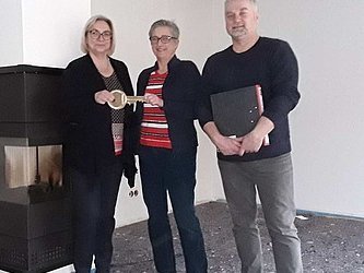 Drei Menschen bei der Hausübergabe