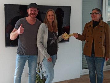 Drei Menschen bei einer Hausübergabe